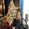 A woman sitting in front of a christmas tree.