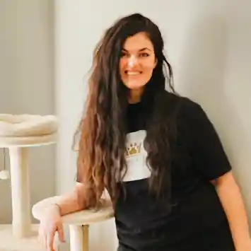 A woman with long hair standing in front of some chairs.