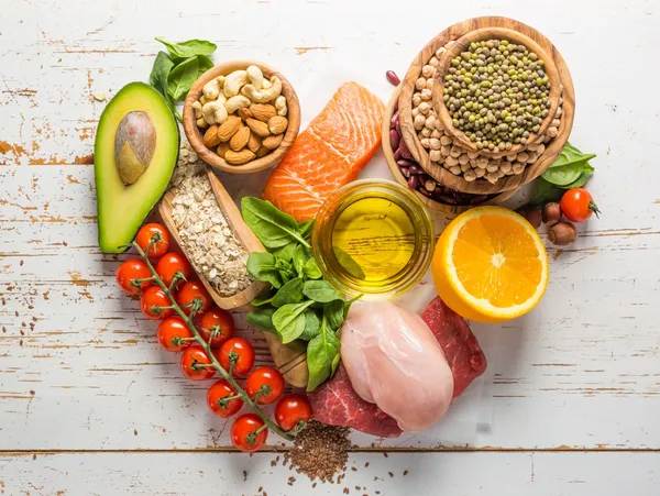 A heart shaped plate of food including meat, vegetables and nuts.