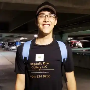 A man wearing glasses and a hat standing in a parking lot.