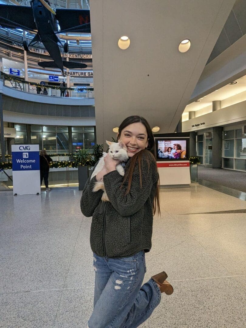 A woman holding a white dog in her arms.